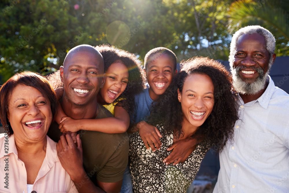 Outdoor Portrait Of Multi-Generation Family In Garden At Home Against Flaring Sun